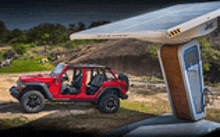 a red jeep is parked next to a solar panel in a field .