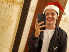 a man wearing a santa hat takes a selfie with his phone