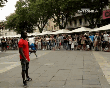 a man in a red shirt is doing a trick in front of a crowd of people and a sign that says " awesome "