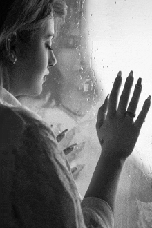 a woman with a ring on her finger is looking out a window