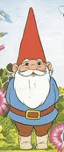 a gnome with a red hat and beard is standing in a field .