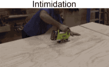 a man is using a jigsaw to cut a piece of wood and the words intimidation are above him