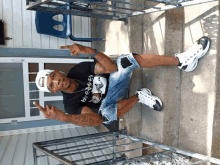 a man wearing a black shirt that says ' bf ' on it sits on the steps of a house