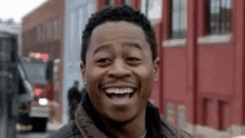 a man is laughing while standing on a street in front of a red building .