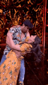 a man is holding a woman in his arms while dancing on a stage