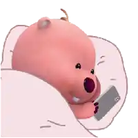 a pink teddy bear is laying under a pink blanket looking at a cell phone