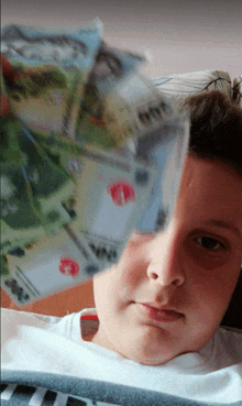 a young boy laying on a couch holding a bunch of money in front of his face