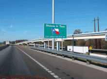 a green sign on the side of a highway that says " welcome to texas "