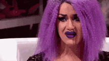 a woman with purple hair and blue lips is crying .