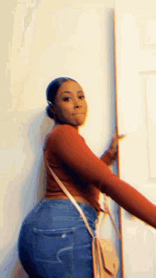 a woman in a red sweater and blue jeans is standing next to a door .