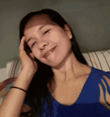 a woman in a blue shirt has her hand on her head