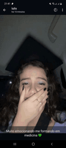 a girl in a graduation cap and gown is covering her mouth with her hands