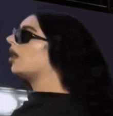 the woman is wearing sunglasses and a black shirt .