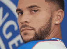 a man with a beard is wearing earrings and a blue and white shirt