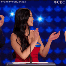 a woman in a red dress is clapping in front of a microphone while wearing a name tag that says onica