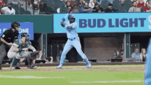 a baseball player is swinging a bat at a ball during a game in front of a bud light sign .