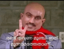 a bald man with a mustache and a red scarf is giving a peace sign .