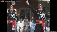 two men in military uniforms are standing in front of a crowd of people and one of them is giving the middle finger