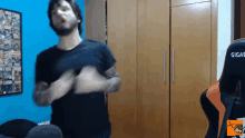 a man in a black shirt is dancing in front of a gigabyte gaming chair