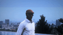 a man wearing sunglasses and a hat stands in front of a city