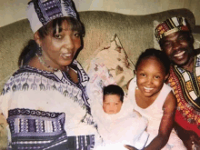 a family posing for a picture with a baby and a woman wearing a hat that says ' african ' on it