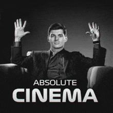 a man in a suit is sitting in a chair with his hands in the air and the words absolute cinema above him