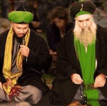 two men with beards and turbans are sitting next to each other in a room .