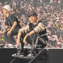 a man is sitting on a stage in front of a crowd .