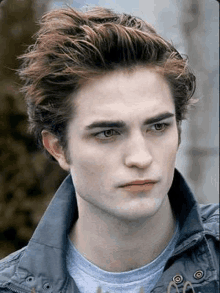 a close up of a young man 's face wearing a jacket and a t-shirt .