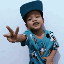 a young boy wearing a blue hat and a blue shirt with mickey mouse on it