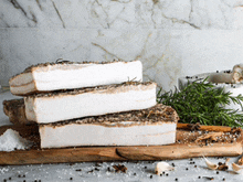 a wooden cutting board with a stack of bacon on top of it