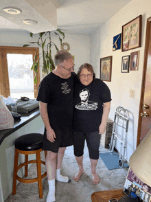 a man and a woman standing next to each other wearing black shirts