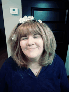 a woman with aluminum foil on her head and a thermostat on the wall behind her