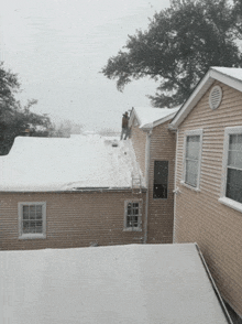 a man is standing on the roof of a house while snow falls