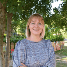 a woman wearing a plaid shirt smiles for the camera