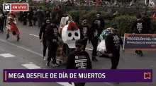 a group of people are walking down a street with a mega desfile de dia de muertos banner behind them