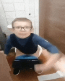 a blurry picture of a boy wearing glasses sitting on a toilet .