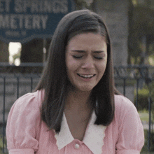 a woman in a pink dress is crying in front of a sign that says " et springs metery "