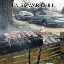 a bottle of water sits on a table next to a grill with cars in the background and the words lcn bizwar chill