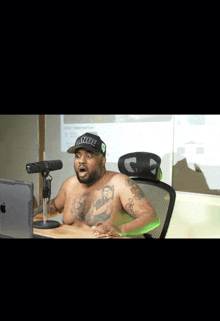 a shirtless man is sitting in front of a microphone wearing a hat that says ' smack ' on it