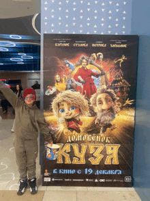 a young boy stands in front of a large poster for a movie called ku3a