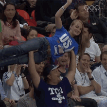 a woman wearing a blue shirt that says us is being lifted by a man wearing a tcl football shirt