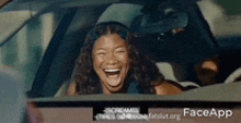 a woman is laughing while sitting in a car with face app written on the bottom of the screen .