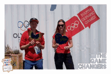 a man and a woman are posing for a photo in front of a sign that says youth olympic games