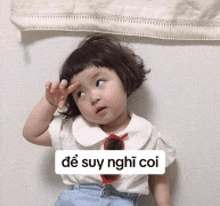 a little girl wearing sunglasses and a white shirt has a sticker on her face that says de suy nghĩ coi