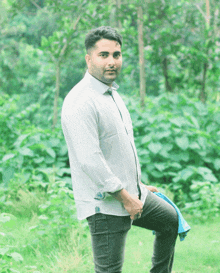 a man in a white shirt and black jeans is kneeling in the grass