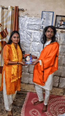 a man in an orange robe is standing next to a woman holding a book