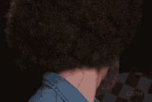 a man with a beard and an afro looks at the camera with a giphy logo in the background