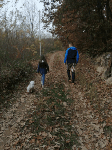 a man and a girl are walking down a path with leaves on it