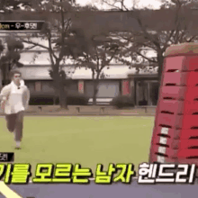 a man is running on a track next to a red stack of boxes .